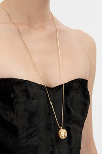 Cropped view CAMILLA AND MARC Eagan Pendant in gold with fine box chain and ruched textured sphere pendant.