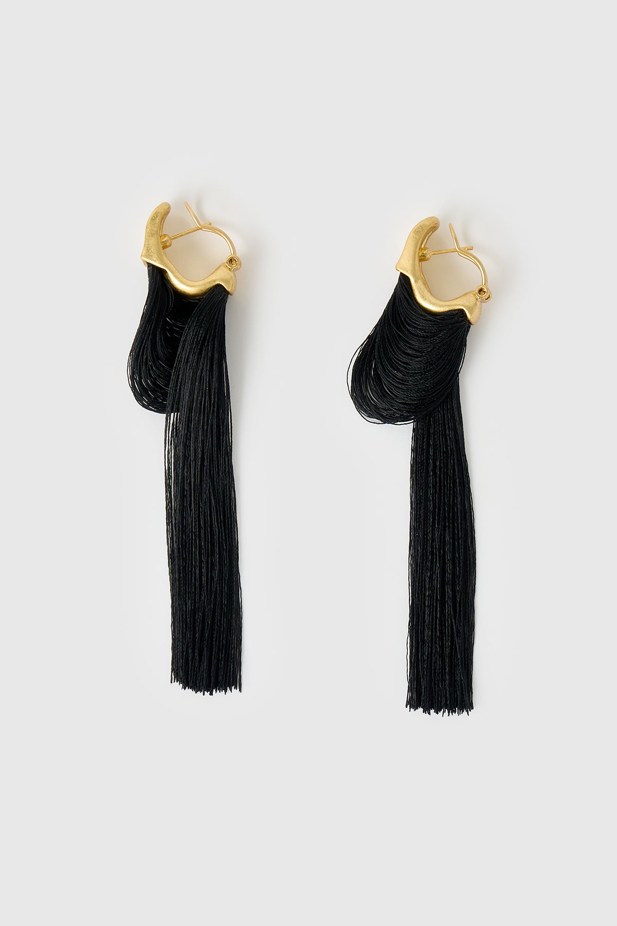 Side view CAMILLA AND MARC Friesian Drop Earrings with 18k gold plating, featuring draped black tassel drop fringing.