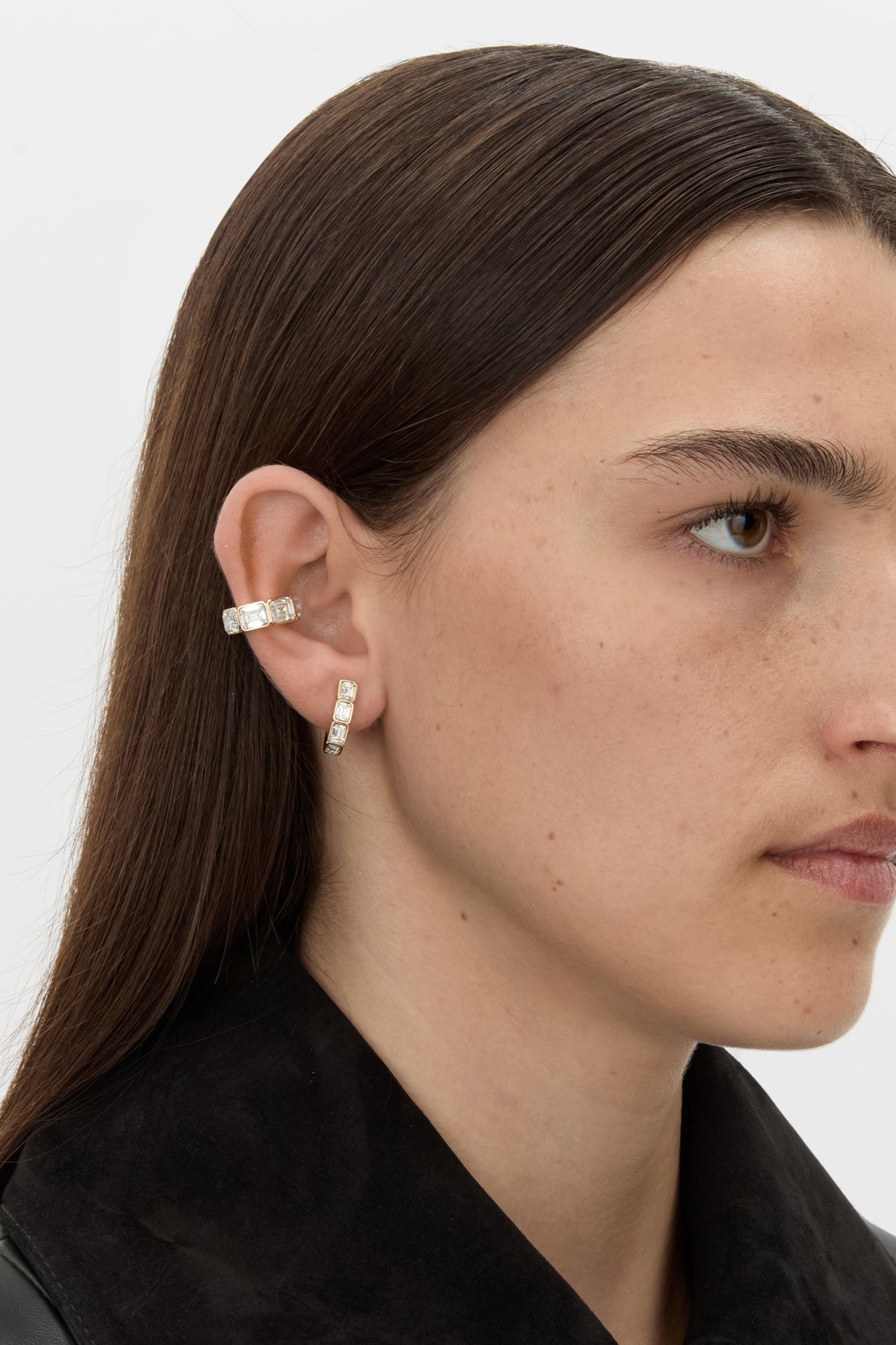 Styled view CAMILLA AND MARC Leighton Huggies in 18k gold finish with emerald cut cubic zirconia stones.