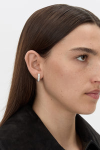 Styled view CAMILLA AND MARC Leighton Huggies in silver finish with emerald cut cubic zirconia stones.