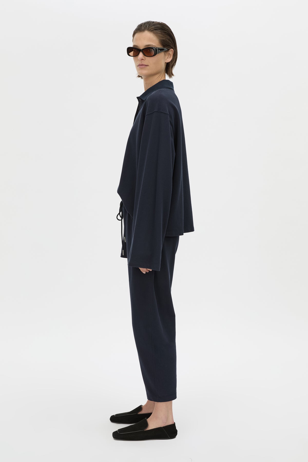 Side view CAMILLA AND MARC Moreno Pique Track Pant in navy with elastic‑encased waistband and embroidered eyelets and drawcord.