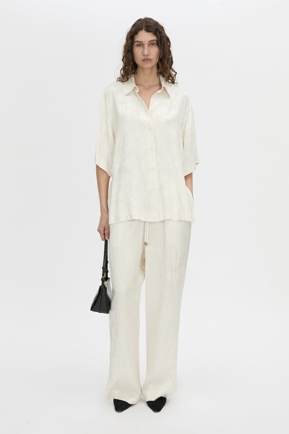 Front-styled view CAMILLA AND MARC Naidee Satin Short Sleeve Shirt in ivory white.