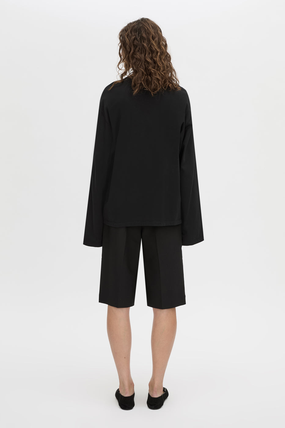 Back view CAMILLA AND MARC Peretti long-sleeve black tee with wide, shaped sleeves.