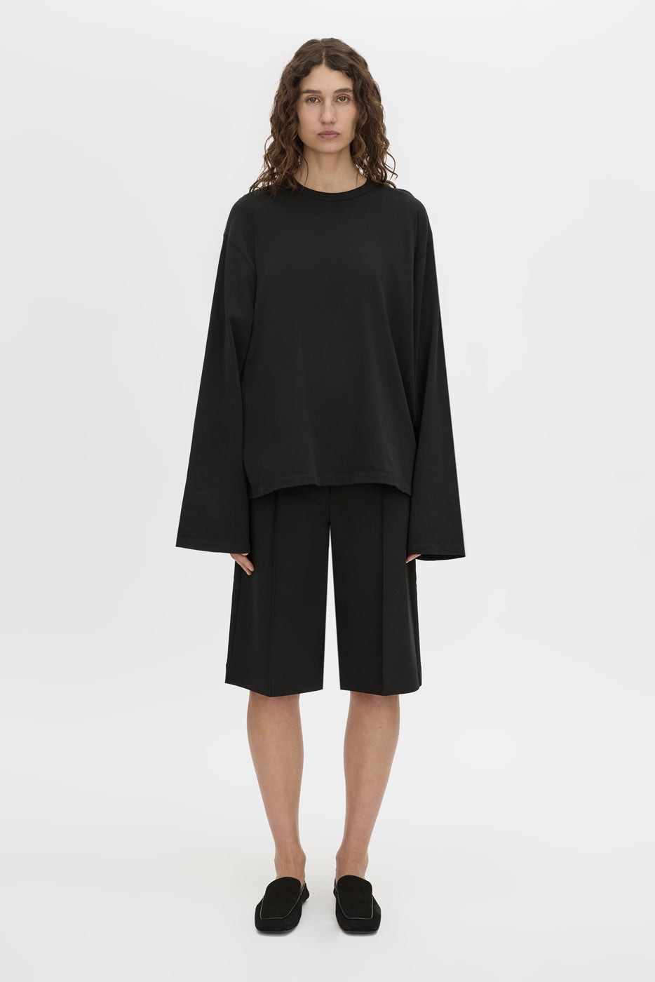 Front-styled-2 view CAMILLA AND MARC Peretti long-sleeve black tee with wide, shaped sleeves.