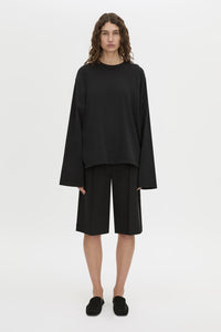 Front-styled-2 view CAMILLA AND MARC Peretti long-sleeve black tee with wide, shaped sleeves.