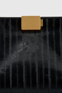 Cropped view CAMILLA AND MARC Poppy Eel Clutch in Black eel‑embossed leather with ribbed gold hardware.