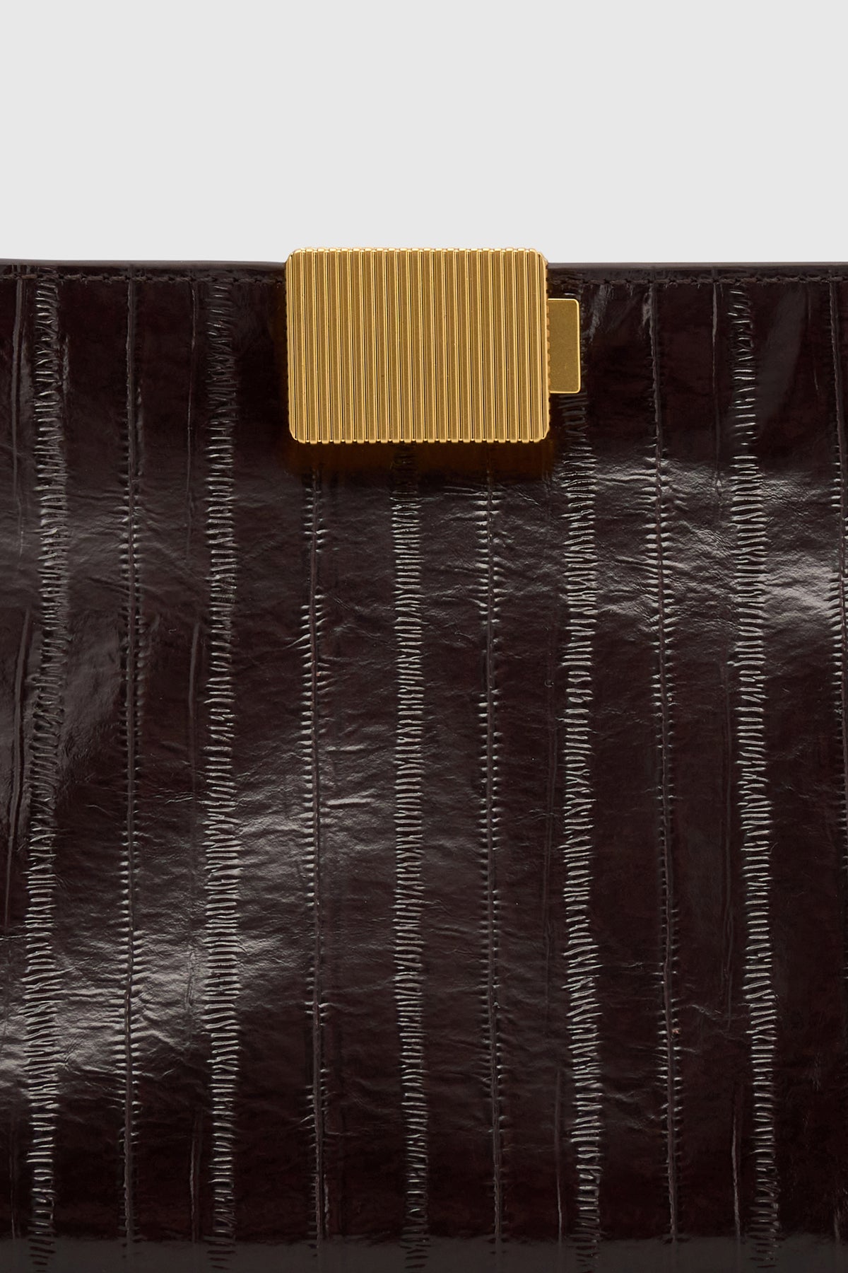Cropped view CAMILLA AND MARC Poppy Eel Clutch in Burgundy eel‑embossed leather with ribbed gold hardware.
