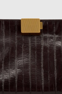 Cropped view CAMILLA AND MARC Poppy Eel Clutch in Burgundy eel‑embossed leather with ribbed gold hardware.