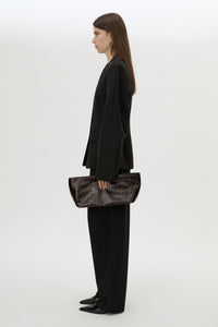 Front styled view CAMILLA AND MARC Poppy Eel Clutch in Burgundy eel‑embossed leather with ribbed gold hardware.