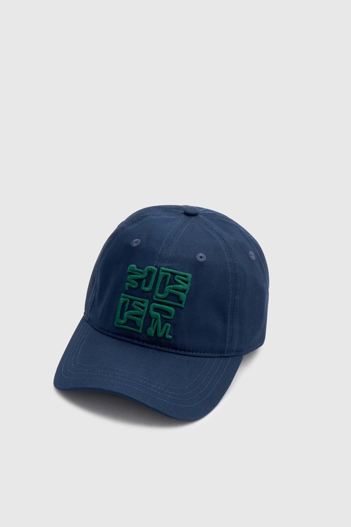 Three-quarter view CAMILLA AND MARC Sonora Embroidered Logo Cap in Deep Ink with embroidered artwork.