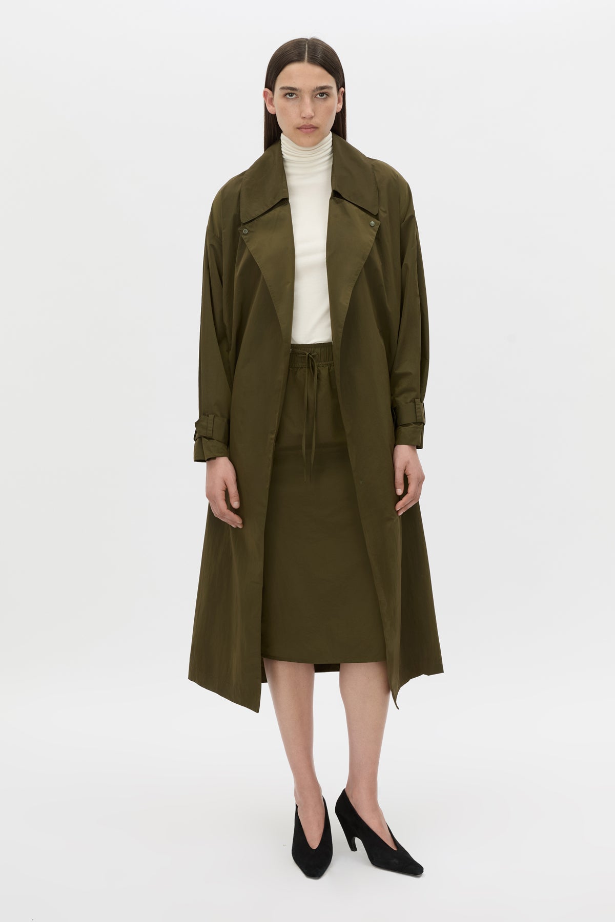 Front-styled view CAMILLA AND MARC Storm Trench Coat in khaki with concealed snap fastenings, in seam pockets and a self tie belt with sleeve straps.
