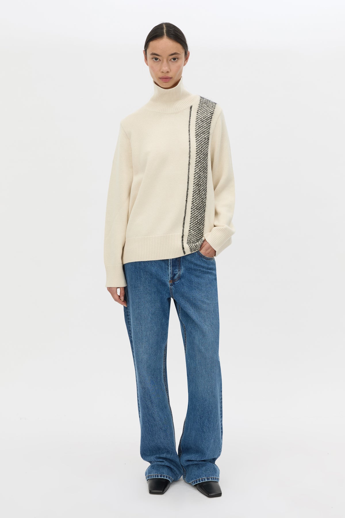 Front-styled view CAMILLA AND MARC Tusk Detail Knit Turtleneck in black with contrast jacquard striped front graphic.