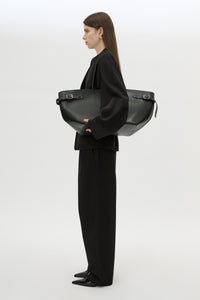 Styled view CAMILLA AND MARC Willa Tote in Black with side strap and buckle detailing and magnetic button closure.