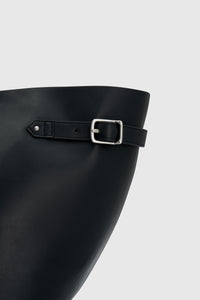 Cropped view CAMILLA AND MARC Willa Tote in Black with side strap and buckle detailing and magnetic button closure.