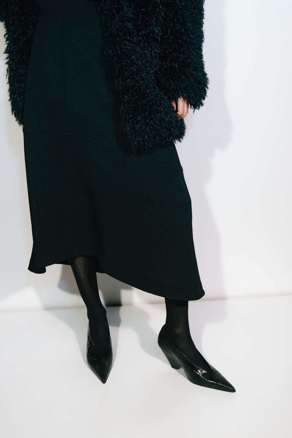 Campaign styled view CAMILLA AND MARC high-waisted Namira Midi Skirt in black with asymmetric hemline.